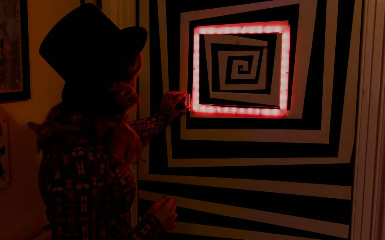 Child wearing a cowboy hat interacting with a neon-lit interactive display featuring concentric geometric patterns.