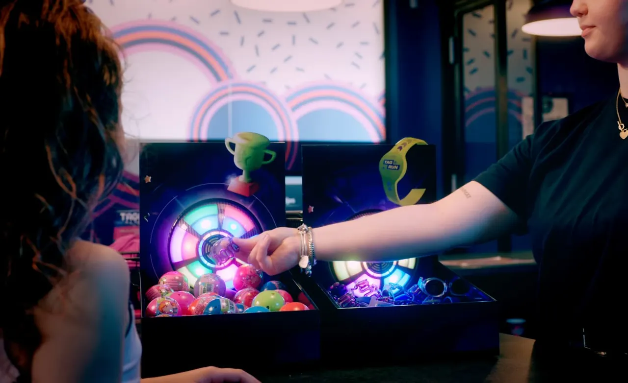 Children playing an illuminated arcade game with colourful balls and neon lights in an indoor entertainment venue.