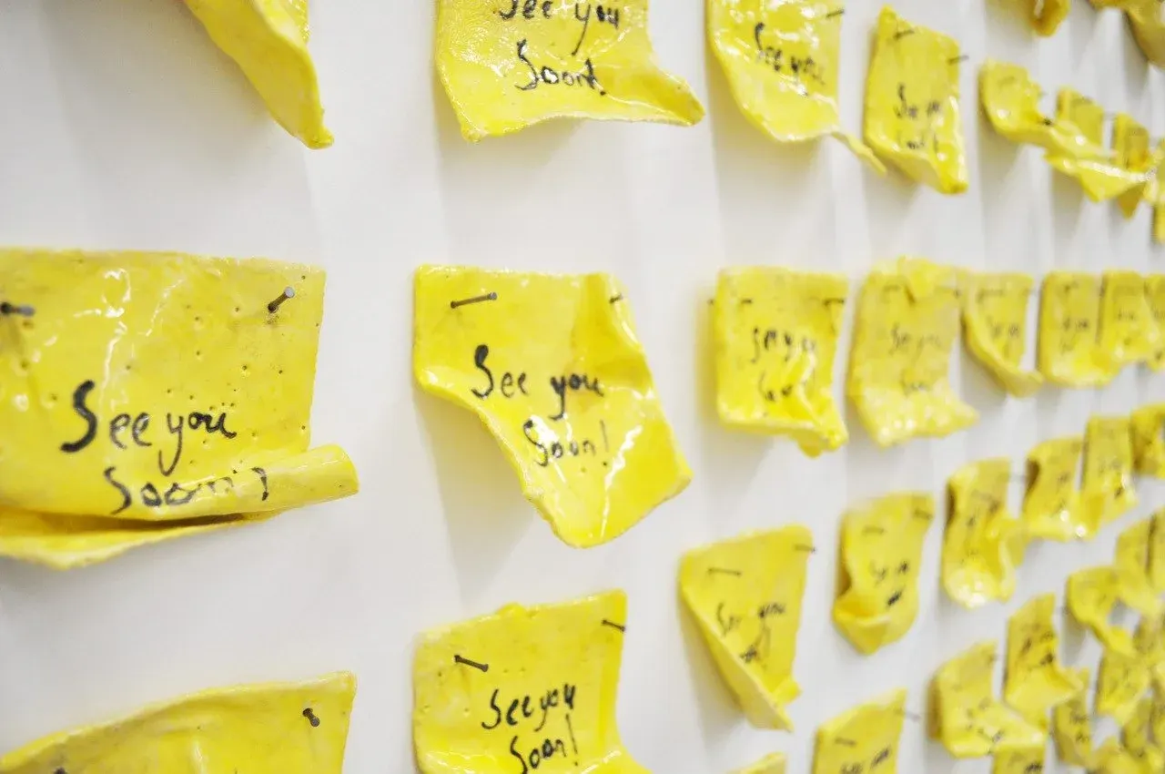 Multiple yellow sticky notes with handwritten messages pinned to a white wall.