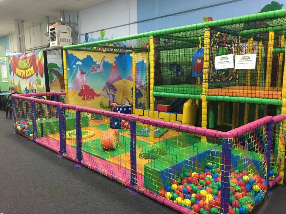 Large soft play structure with colourful netting, inflatable obstacles and ball pit in an indoor play area.