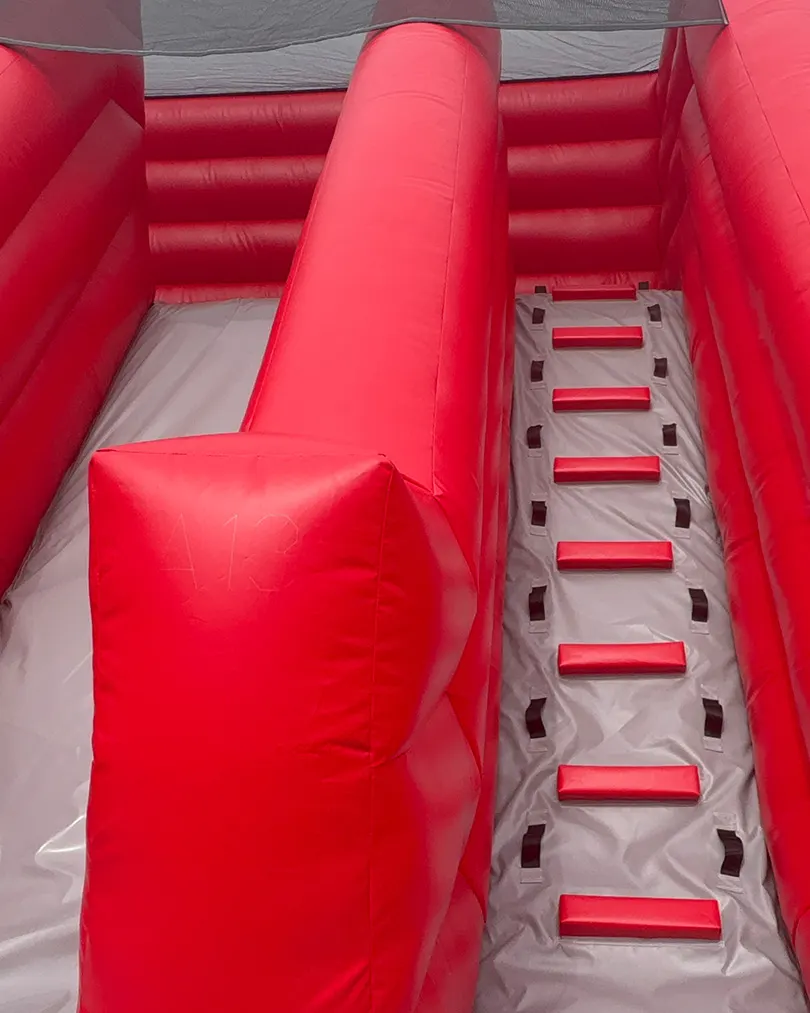 Interior view of a red inflatable obstacle course with a tunnel and climbing steps.