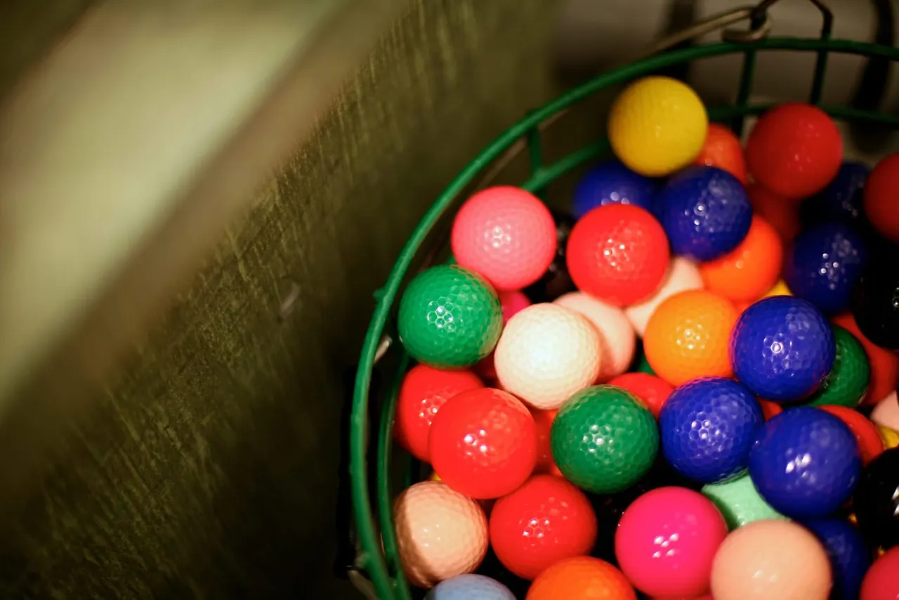Colourful golf balls in a green basket.