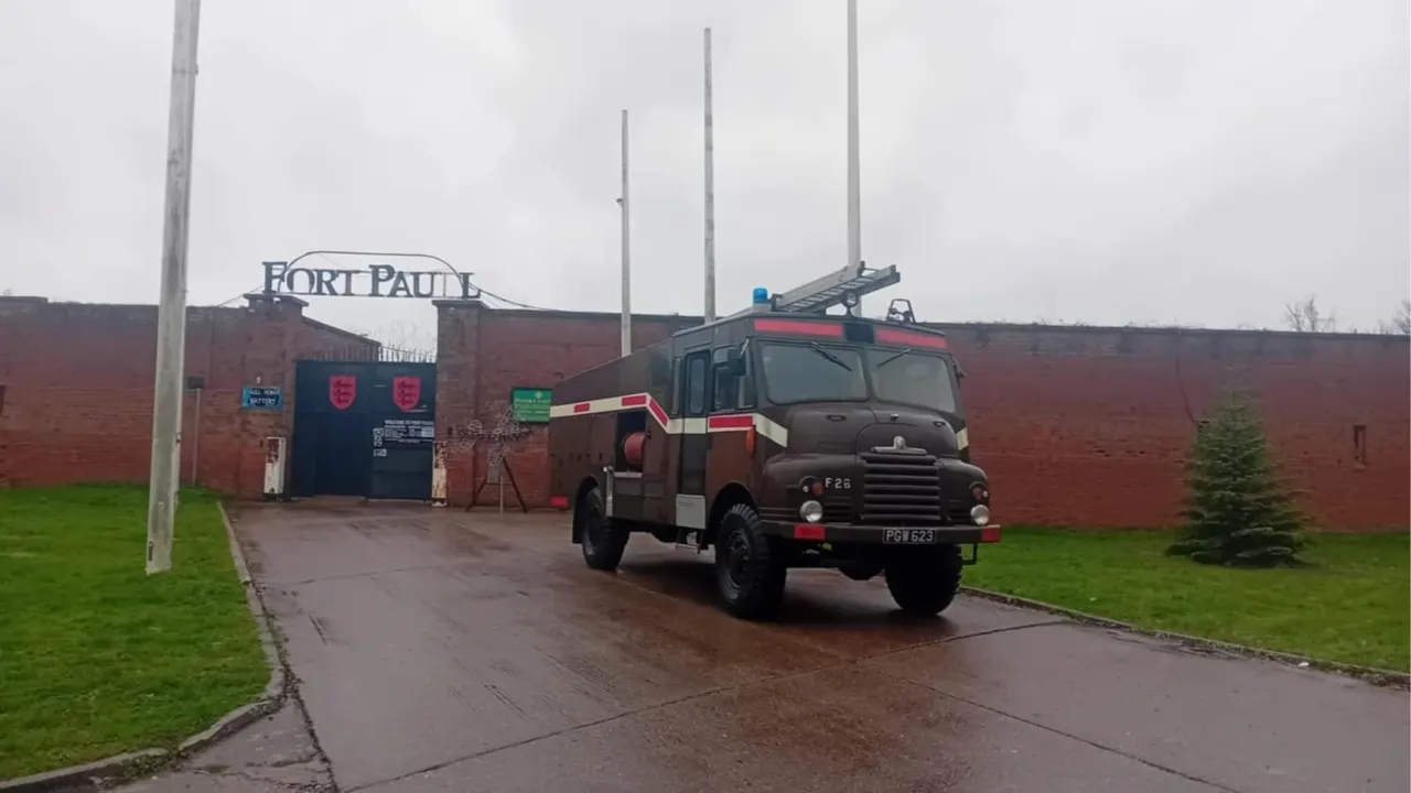 Vintage fire engine parked outside red brick fort building with Fort Paull signage.