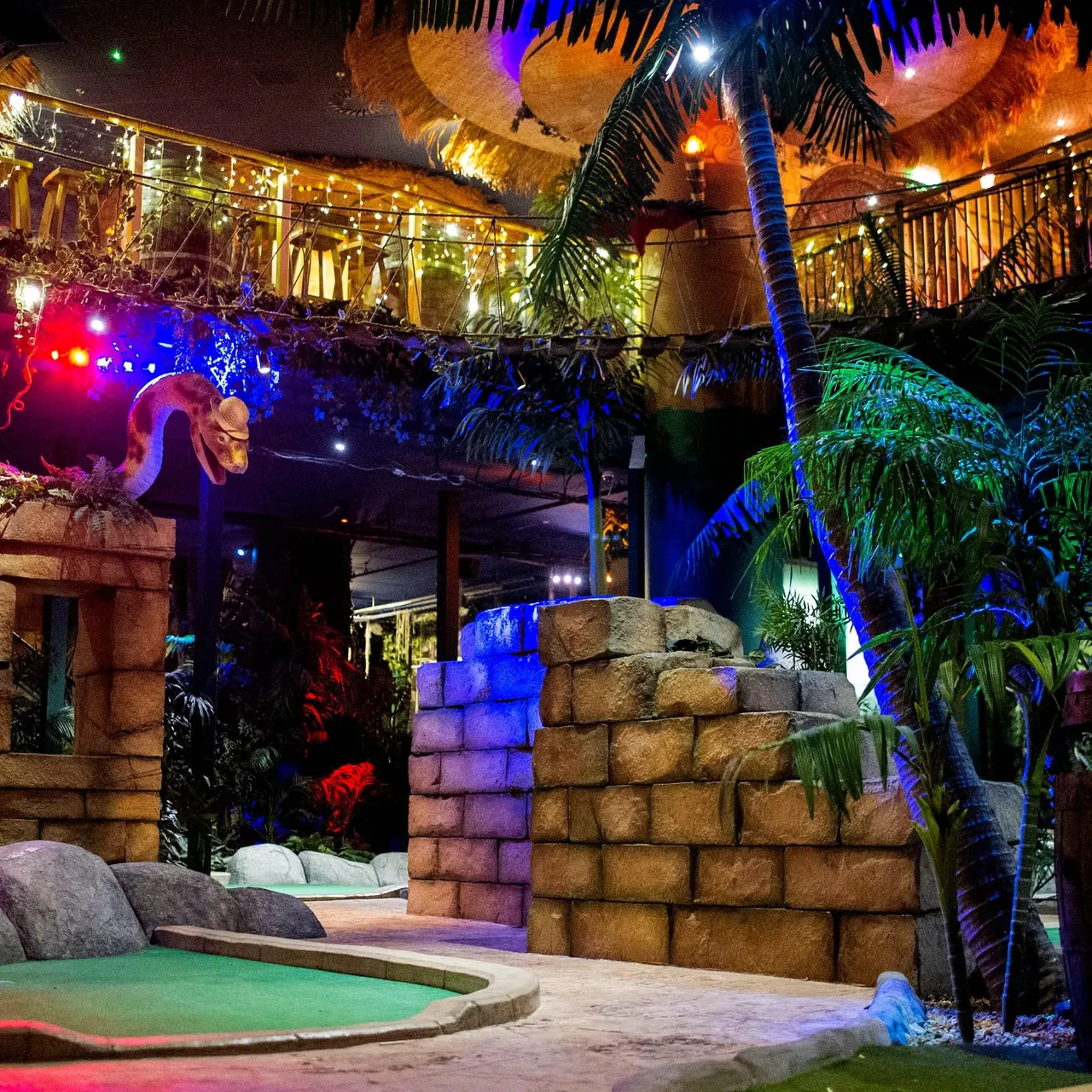 Indoor adventure golf course with snake, palms and rope bridge