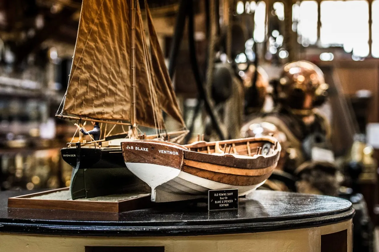 Detailed scale models of wooden sailing boats and fishing vessels displayed in a maritime museum exhibit.