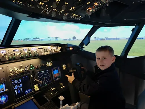 Young boy at the controls in an aircraft flight simulator cockpit.