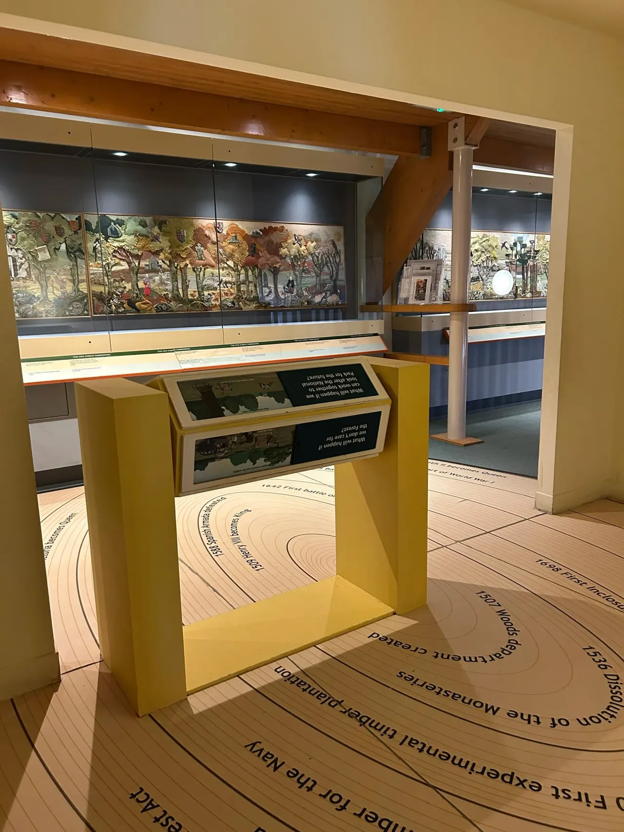 Museum interior showing yellow display cases with illustrated panels and interactive exhibits on the wooden floor.