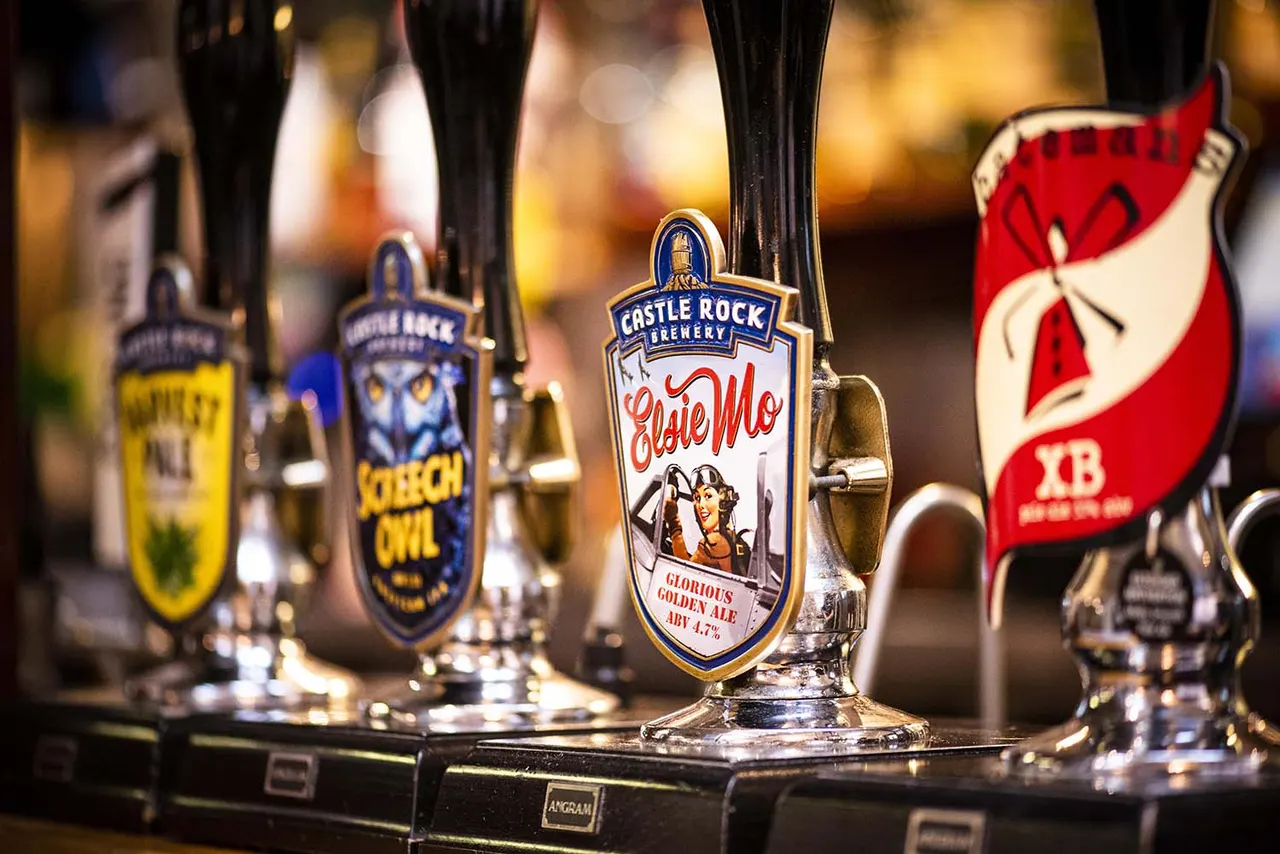 Multiple beer pump handles lined up at a bar, including Castle Rock Brewery's Olde Mlo ale.