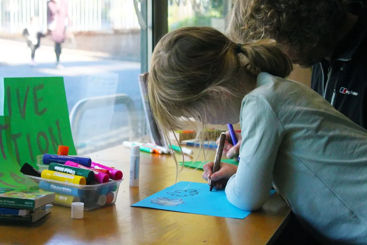 Child drawing with markers at a table during an arts and crafts activity indoors.