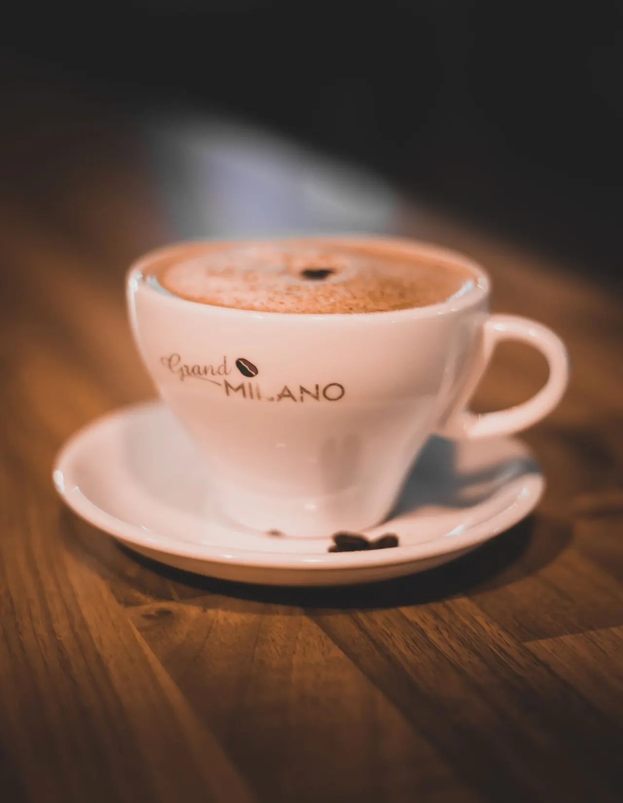 A cup of coffee with latte art sits on a wooden table.
