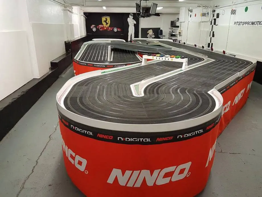 Indoor slot car racing track with multiple curved lanes and racing circuits in a dedicated venue.
