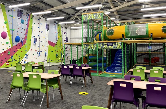 Indoor play area with climbing walls, soft play structures, and seating for children and families.