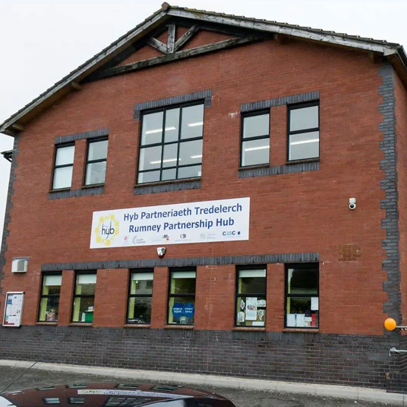 Red brick community building with "Rumney Partnership Hub" signage and ground-floor windows.