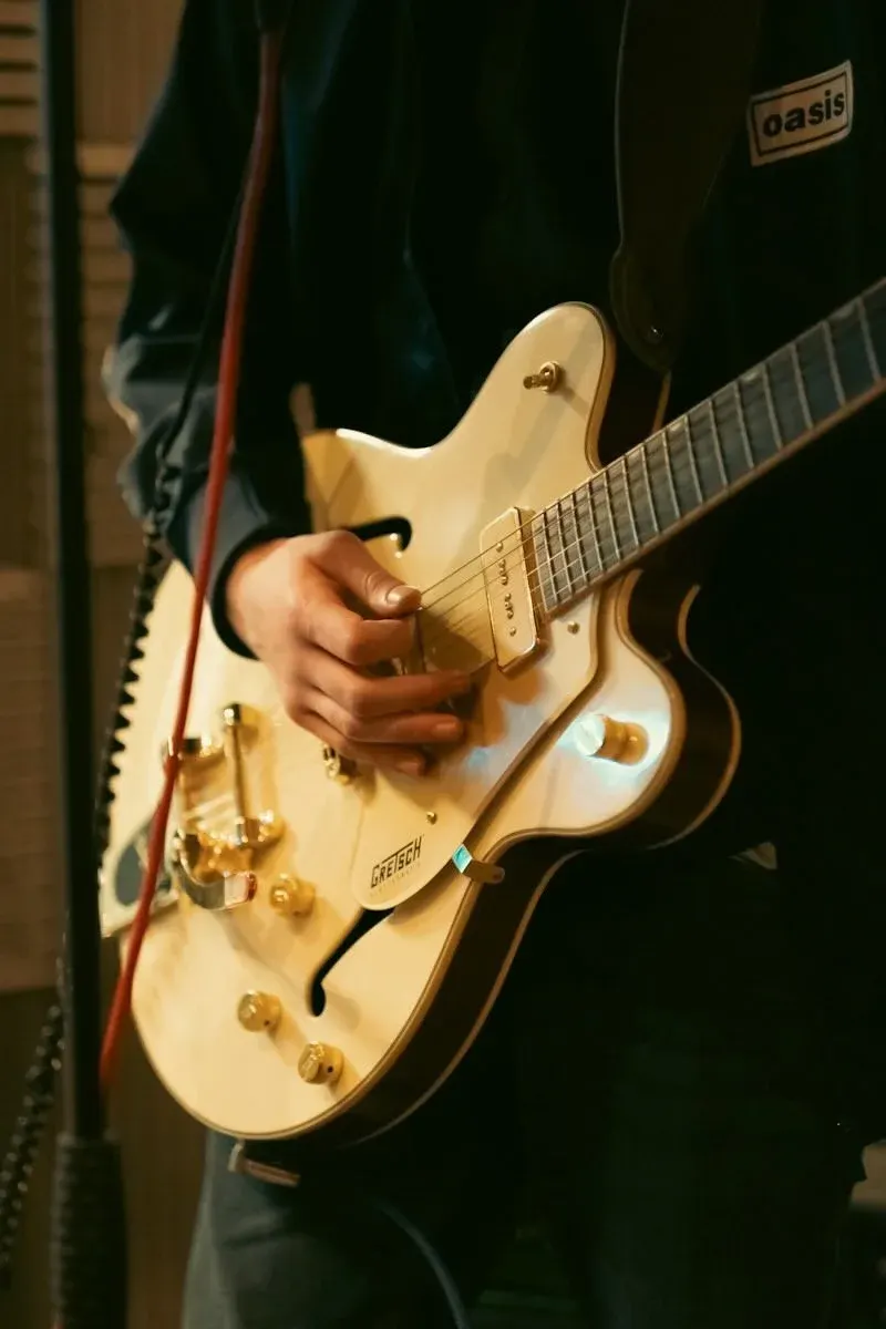 Musician playing a cream-coloured electric guitar during a performance.