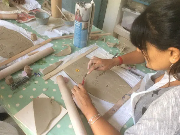 A person working on a pottery wheel, shaping clay during a ceramics class.