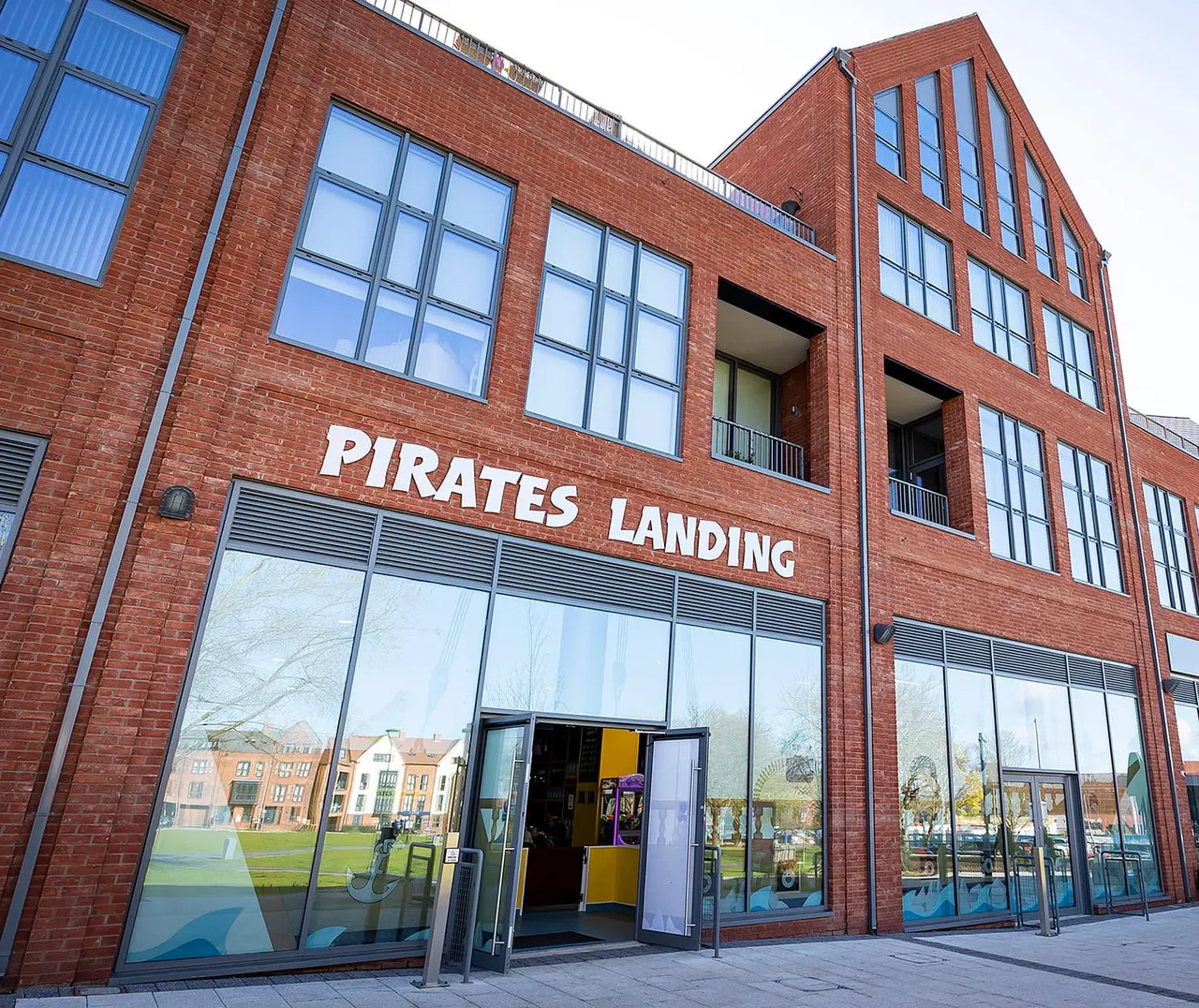 Exterior of a red-brick leisure building with "Pirates Landing" signage, large windows and entrance doors.