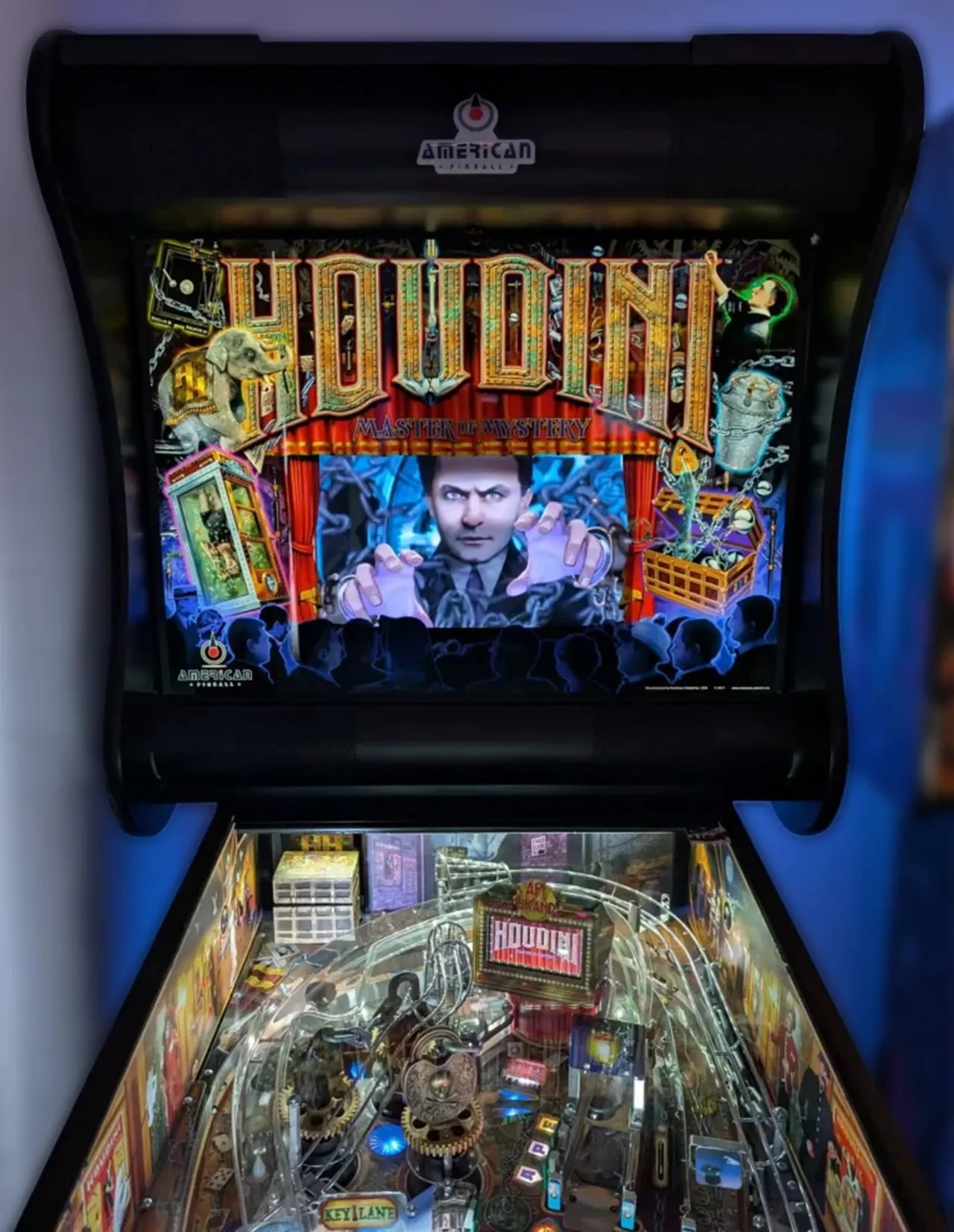 A vintage Houdini-themed pinball machine with illuminated display screen showing a magician and colourful playfield with mechanical elements below.