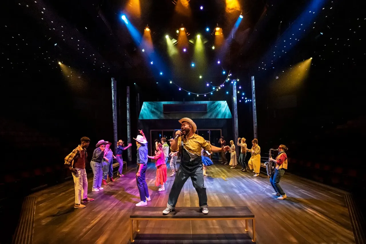 Performer in yellow cowboy outfit singing on stage with children dancing around him under colourful stage lighting.