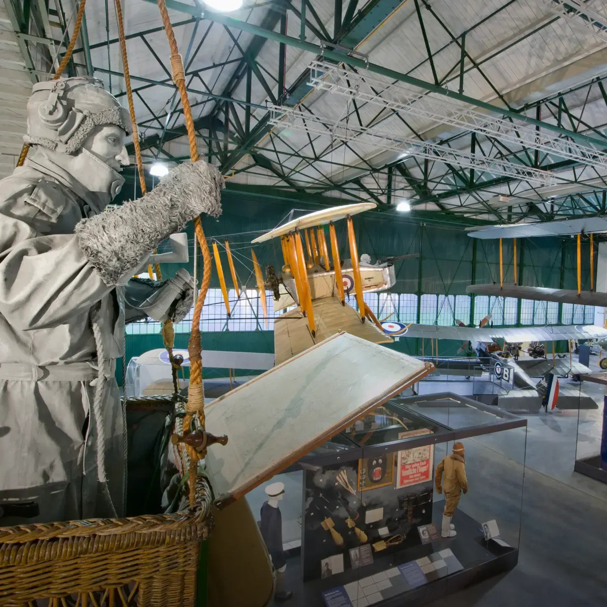 Historic aircraft and aviation memorabilia displayed in a large hangar with vintage biplanes suspended from the ceiling.