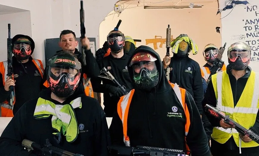 Group of players wearing protective masks and tactical gear posing with airsoft weapons indoors.