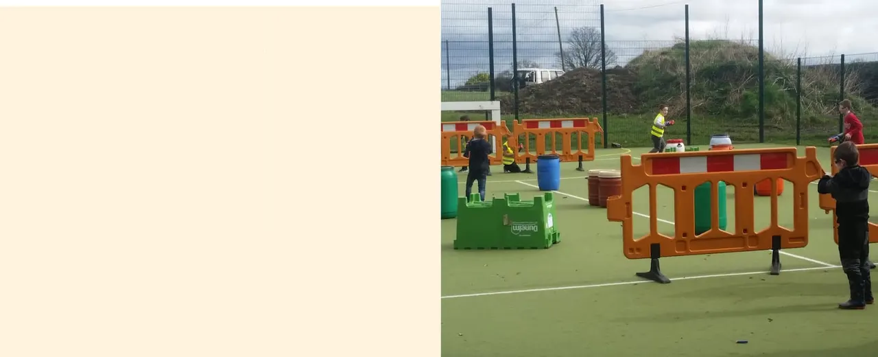 Children navigating an outdoor agility course with orange and green obstacle equipment on an all-weather surface.