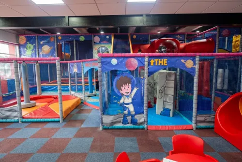 Indoor soft play area with colourful ball pits, slides and climbing structures for children.