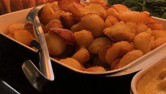 Golden-fried potatoes and onion rings served in a metal basket with a handle.