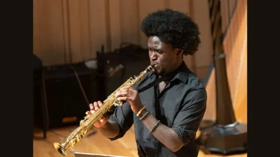 Man playing saxophone on stage at Stoller Hall during a performance.