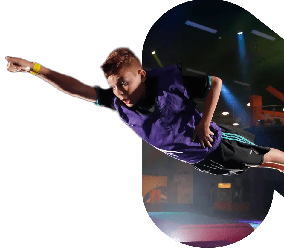 Child flying in the air indoors at an activity centre with coloured lighting.