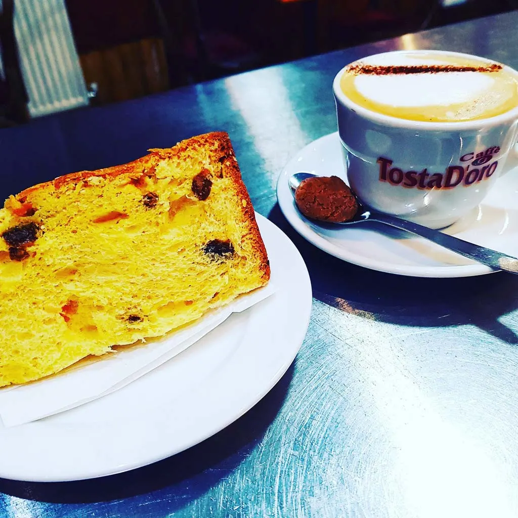 Toasted bread with raisins and a cappuccino served on a blue table at a café.
