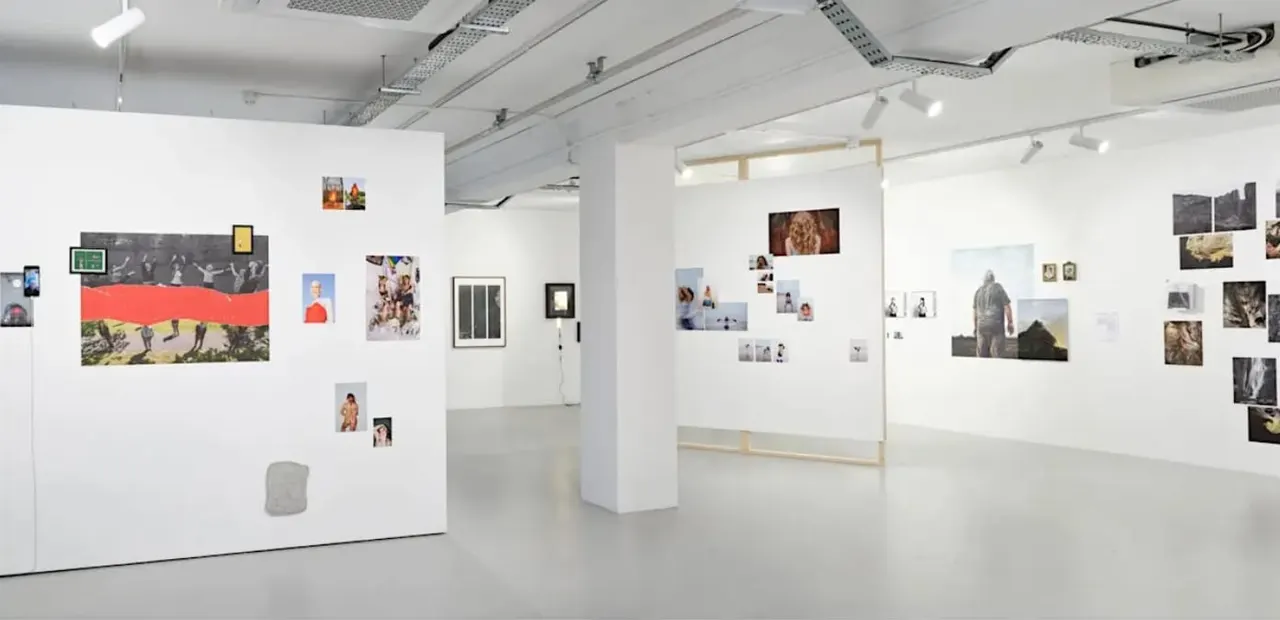 Interior of a contemporary art gallery with white walls displaying various photographs and artworks.