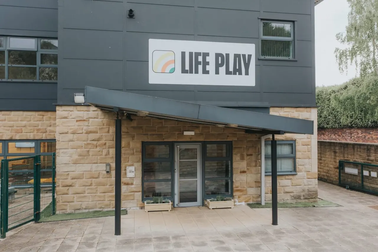 Exterior of a modern leisure venue building with "LIFE PLAY" signage, brick and cladding facade, glass entrance doors and windows.