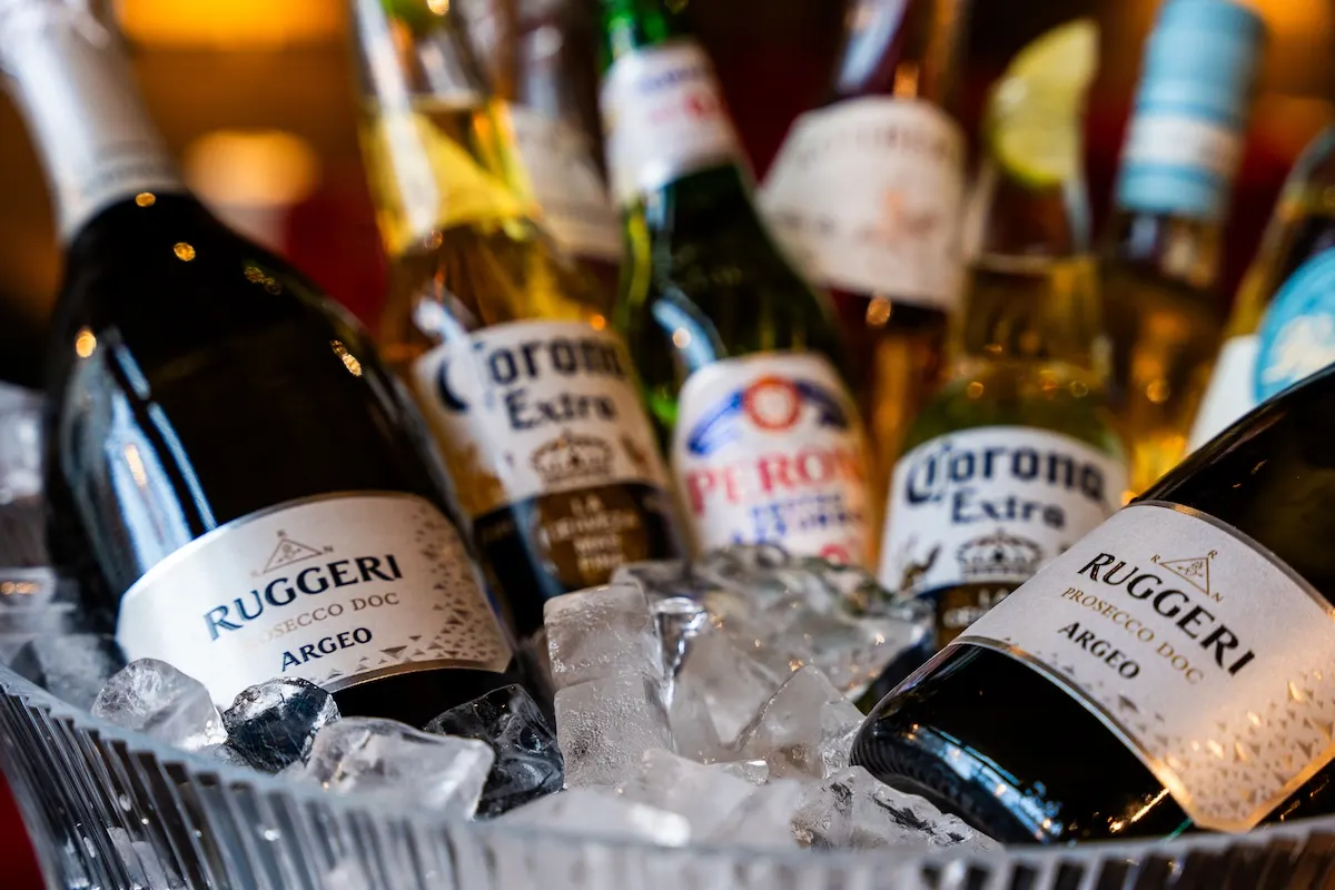 Assorted beer and wine bottles chilling on ice in a bucket at a bar.