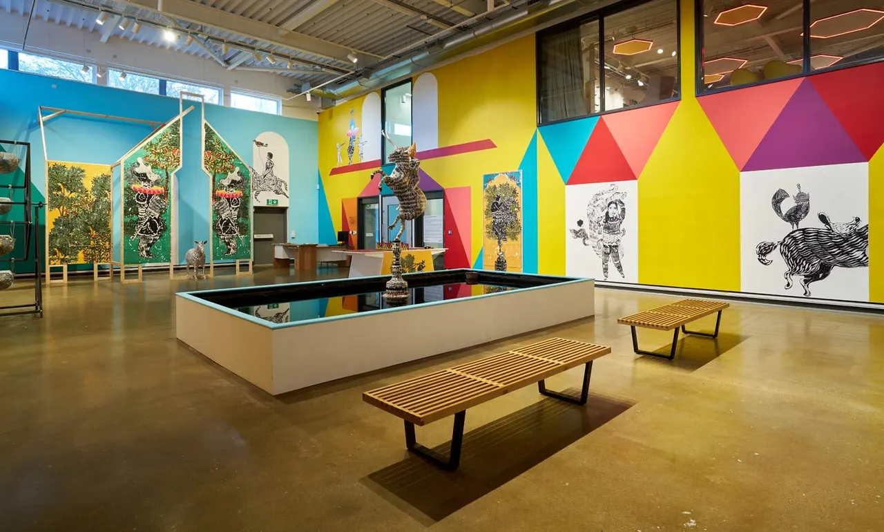 Colourful indoor exhibition space with wooden benches, display panels featuring animal illustrations, and interactive installations.