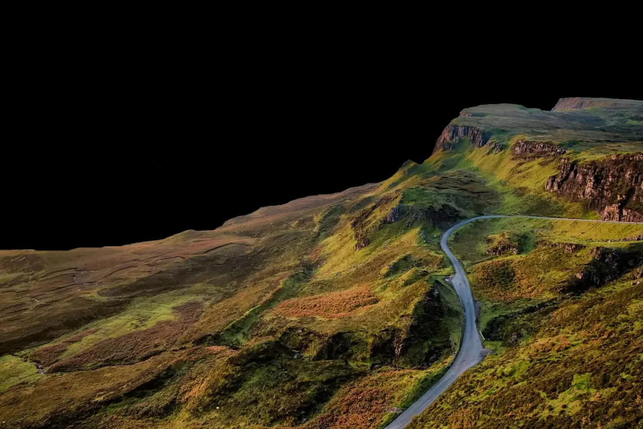 Winding road through dramatic Icelandic mountain landscape with moss-covered terrain and basalt cliffs.