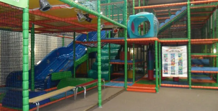 Colourful indoor play structure with slides, climbing frames and tunnels in a softplay facility.