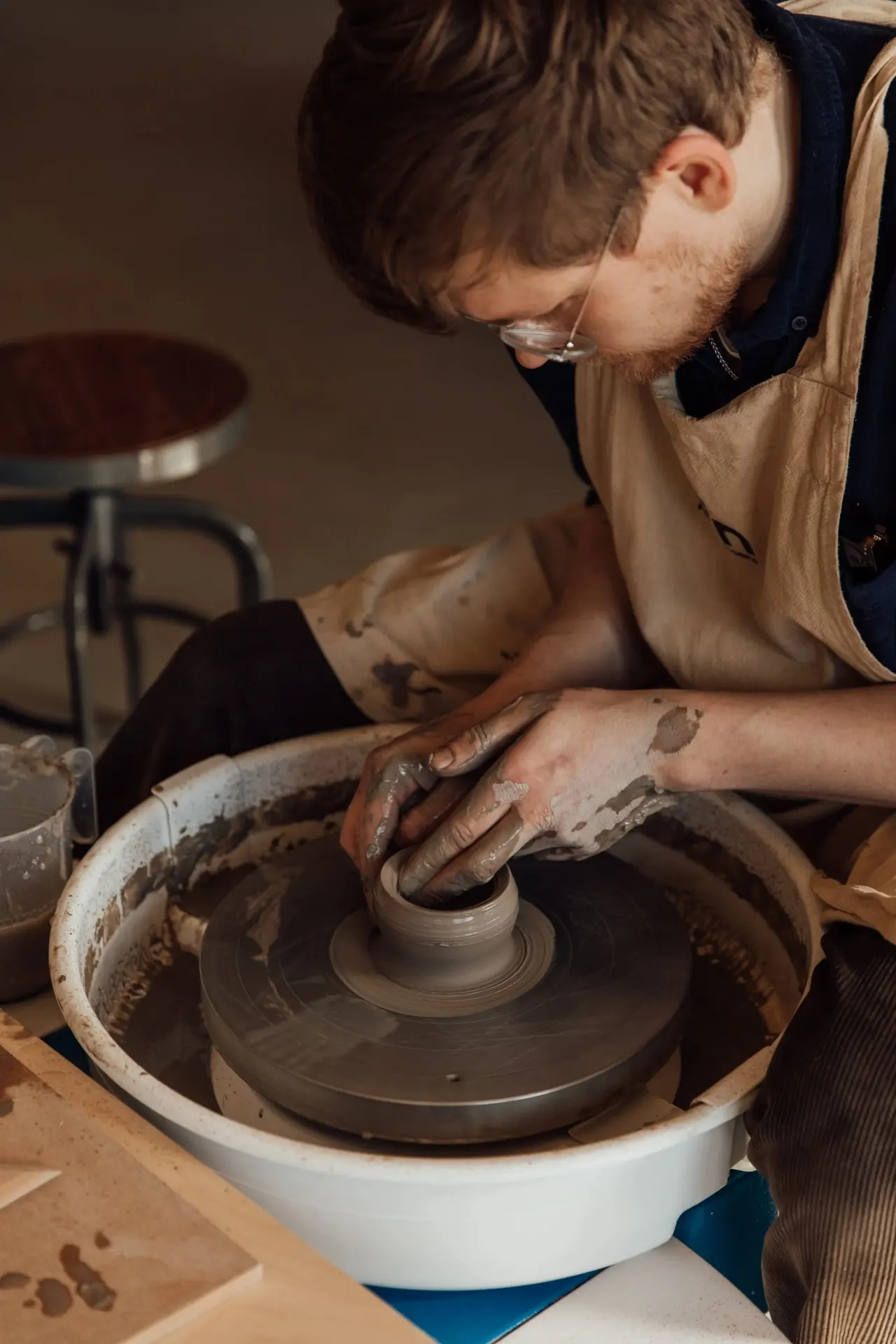 Person shaping clay on a pottery wheel during a hands-on ceramics workshop.