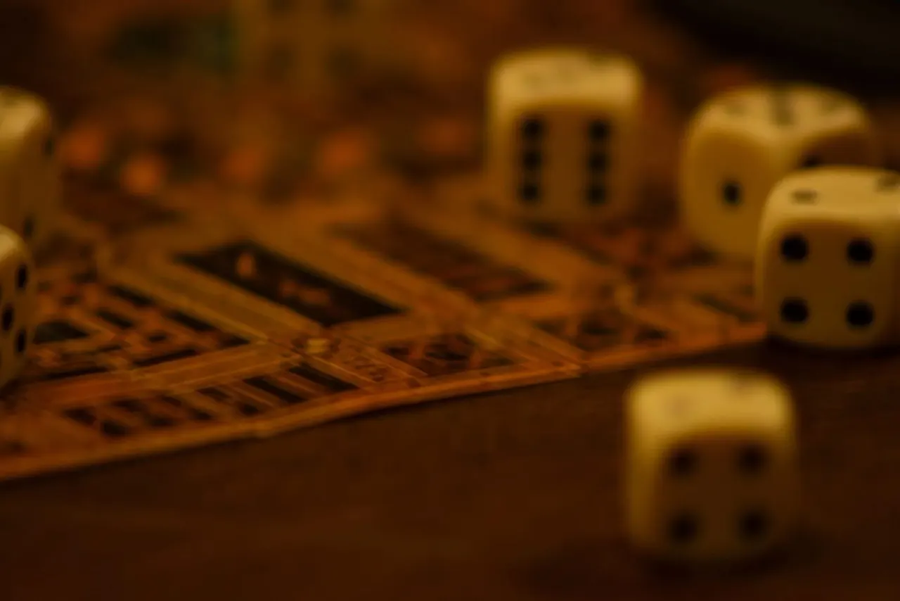 Cream-coloured dice scattered on a wooden board game surface in soft warm lighting.