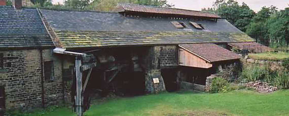 Stone farm buildings with moss-covered roofs and open barns surrounding a grassy yard.