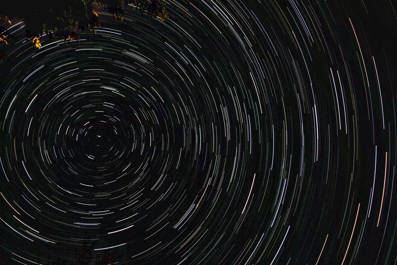 Long-exposure night sky photograph showing circular star trails radiating from the north celestial pole.