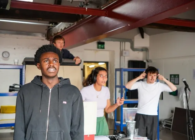 Young people participating in a drama or theatre workshop activity in an indoor studio space.