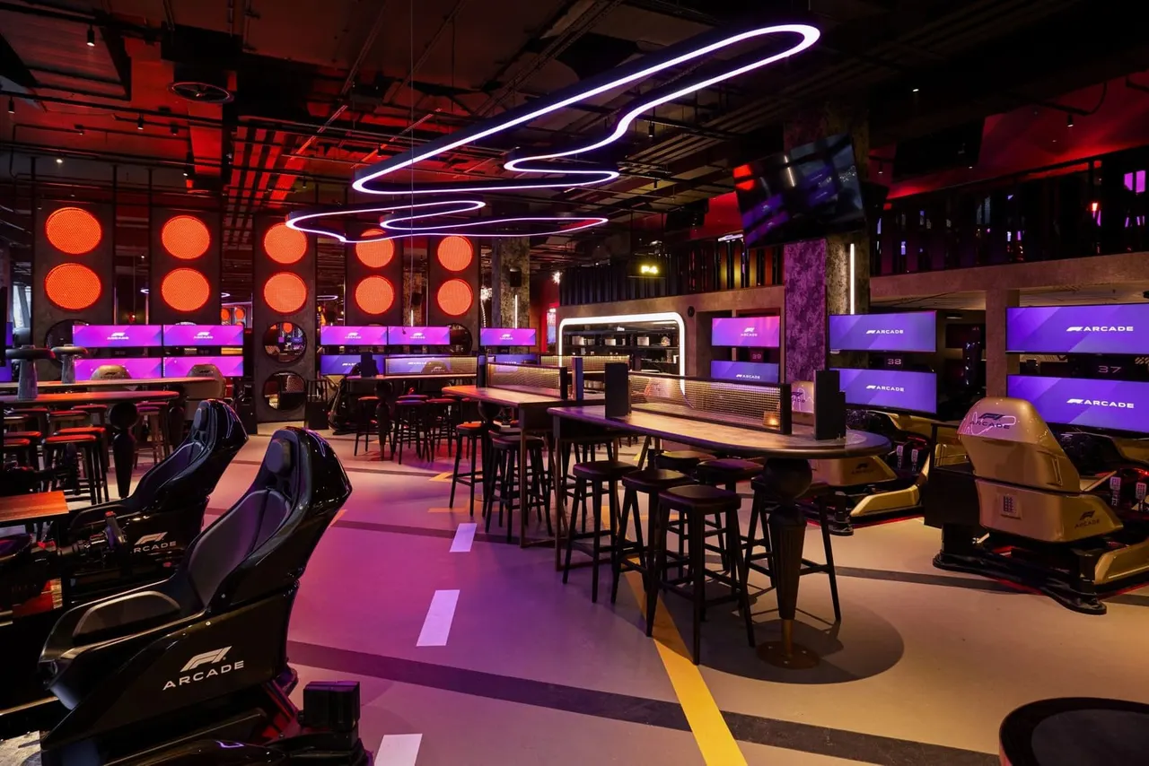 Neon-lit indoor racing arcade with gaming seats, bar seating, and red and purple ambient lighting throughout the space.
