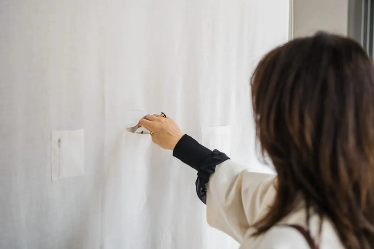 Woman viewing artwork on white wall in gallery space.