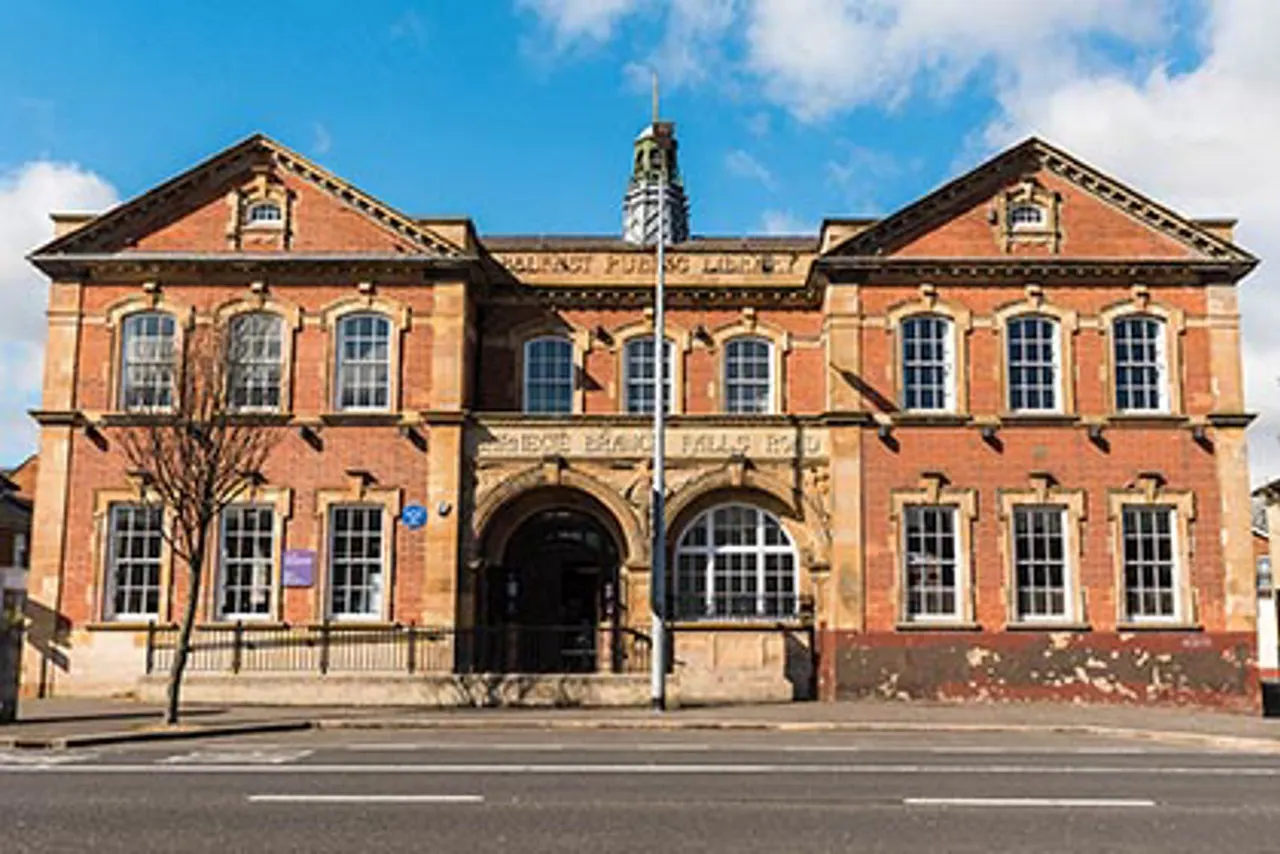 Victorian red-brick public library building with symmetrical facade, multiple windows, central entrance, and flagpole.