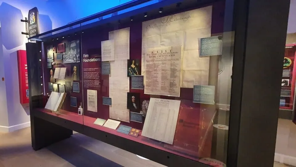 Museum display case with historical documents, portraits and artefacts related to Scottish foundations and heritage.