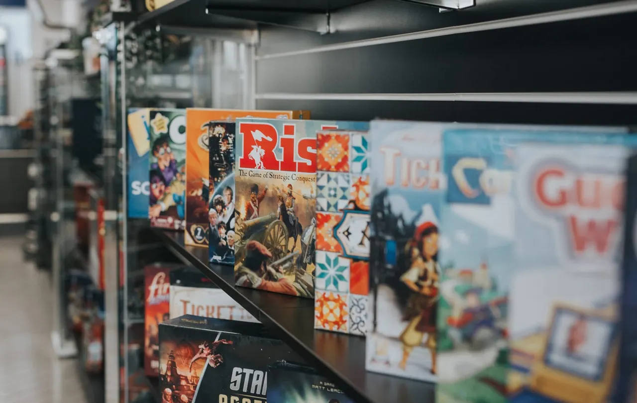 Board games including Risk displayed on a shelf in a games café.