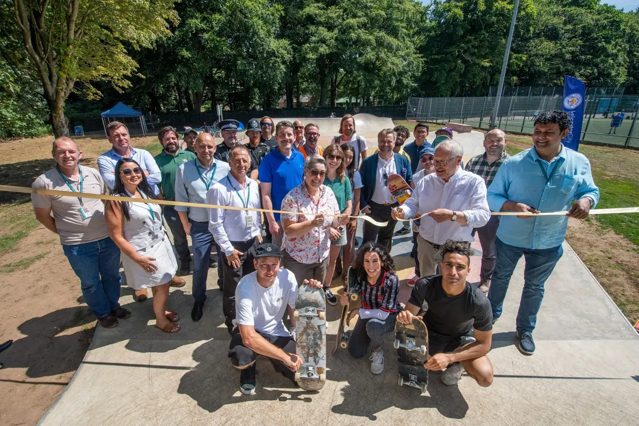 Large group of adults and young people at a ribbon-cutting ceremony at a skate park, holding skateboards.