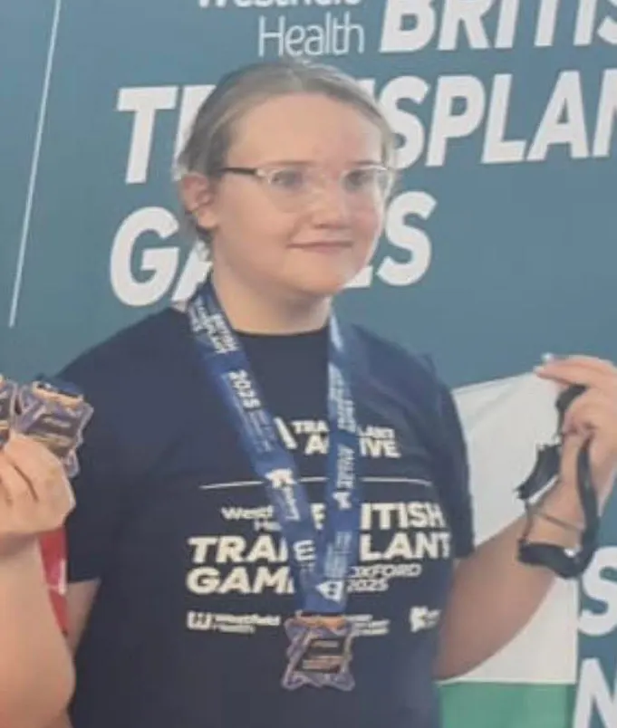 Young athlete displaying medals at an awards ceremony at a swimming competition.