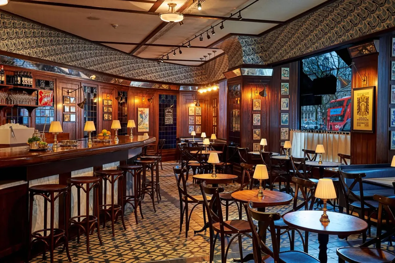 PHOTOGRAPH

Elegant wood-panelled bar and lounge with small tables, chairs, and a long counter, decorated with vintage posters and warm lighting.