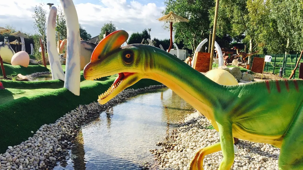 Dilophosaurus statue and hole 17 flag on Lost World dinosaur golf course